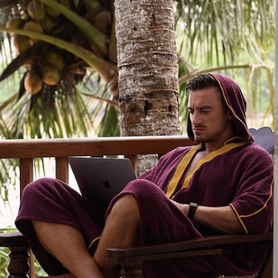 Pete Kaminski wearing Beach Bisht® hoodie bathrobe plum color from beach bisht terry towel beach cover up kimono collections